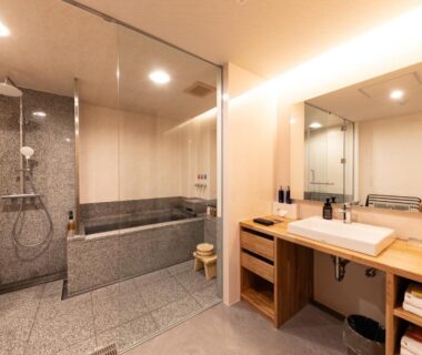 Indoor stone tub, glass shower partition and wooden vanity in Kawakamiya Kasuitei bathroom, Gifu