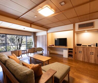 Spacious wood lounge with sofa, low table and garden view at Kawakamiya Kasuitei, Gifu, Chūbu