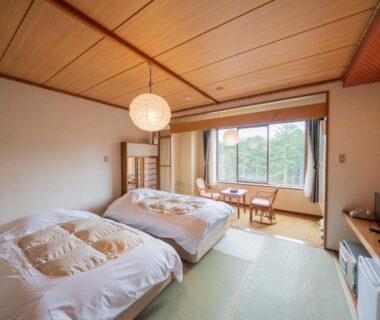 Tatami room with twin beds, low table by window and garden view at Kawayu Kanko Hotel Hokkaidō