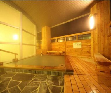 Indoor wooden onsen bath with tiled floor and bench at Kawayu Kanko Hotel, Hokkaidō