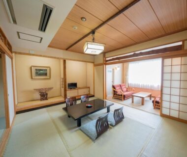 Traditional tatami room with low table, cushions, shoji screens and seating alcove at Kawayu Kanko Hotel in Hokkaidō