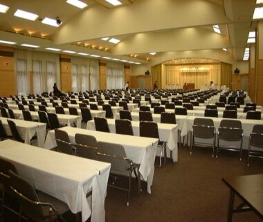 Spacious conference hall with rows of tables and chairs and a front stage at Kawayu Kanko Hotel Hokkaidō