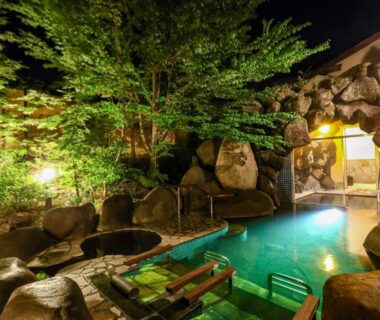 Rock-bordered outdoor onsen under illuminated trees at Keiryuso Siorie, Nagano