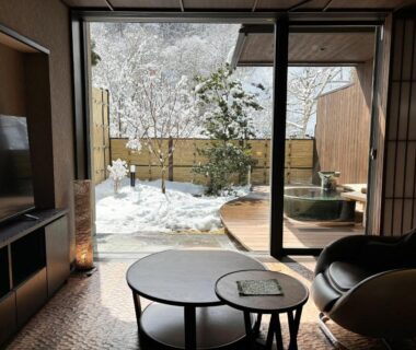 Sliding glass view of snowy garden and wooden outdoor bath at Keiryuso Siorie Nagano