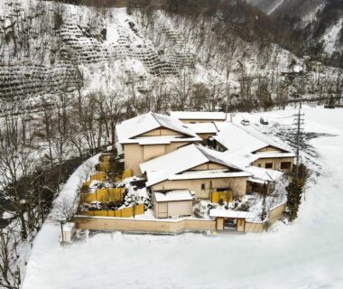 Snow-covered traditional ryokan complex with wooden buildings in Nagano mountain valley