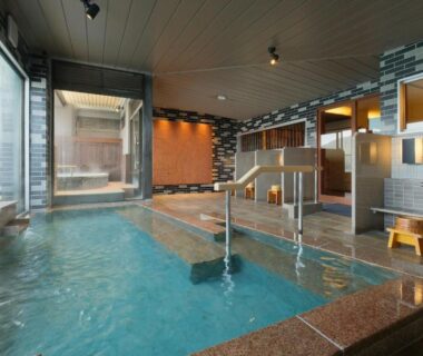 Indoor tiled communal bath with shower stations and stools at Keishokan Sazanamitei in Hiroshima Prefecture