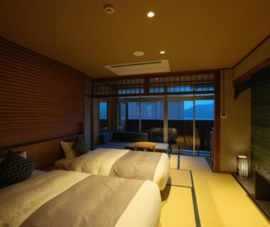 Tatami-floored twin room with low beds, shoji-style sliding doors and balcony at Keishokan Sazanamitei in Hiroshima