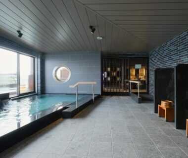 Indoor bathing area with tiled pool and wooden stools at Keishokan Sazanamitei, Hiroshima, Chūgoku