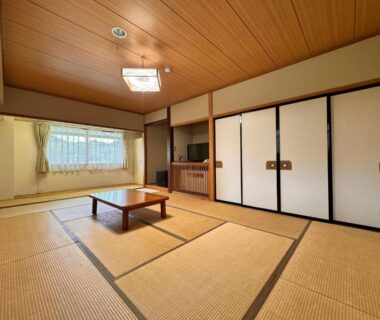 Spacious tatami room with low table sliding fusuma doors and window at Kidoike Onsen Hotel Nagano