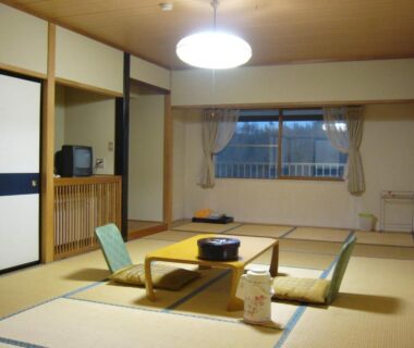Traditional tatami room with low table, floor chairs, sliding closets and window at Kidoike Onsen Hotel, Nagano