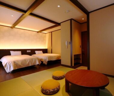 Tatami area with low round table and twin beds at Kii no Matsushima in Mie