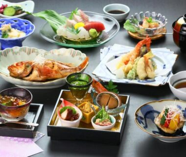 Assorted traditional Japanese multi-course dishes including sashimi, tempura and grilled fish on lacquer trays