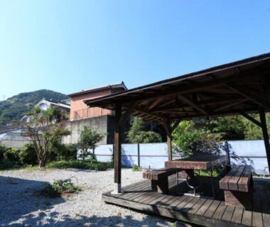 Wooden pergola with benches in gravel courtyard, mountain backdrop at Kii no Matsushima, Mie, Kansai Japan