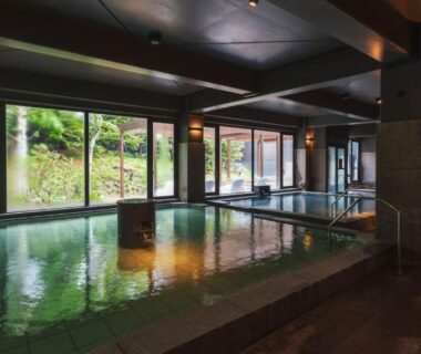Large indoor onsen pool with floor-to-ceiling windows at Kiki Shiretoko Natural Resort in Hokkaidō