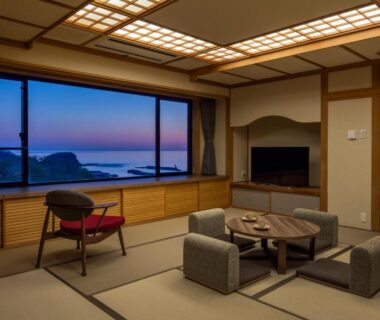 Tatami room with low table and chairs overlooking coastal sunset at Kiki Shiretoko, Hokkaido