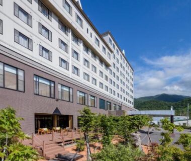 Large resort exterior with terrace seating at Kiki Shiretoko Natural Resort, mountain backdrop in Hokkaidō