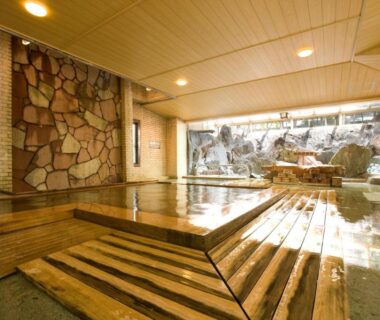 Wooden indoor onsen bath with stone wall at Kikori ryokan in Yamanashi, Chūbu