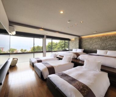 Large room with low beds and floor-to-ceiling windows overlooking greenery at Kikunoya, Hiroshima