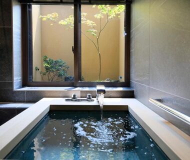Indoor Japanese soaking tub with window overlooking a small courtyard at Kikunoya in Hiroshima
