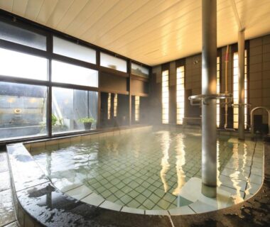 Steaming indoor tiled onsen pool with windows and wooden ceiling at Kikunoya, Chūgoku, Hiroshima, Japan