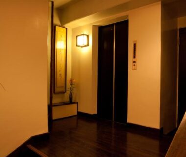 Narrow wooden corridor with steps and elevator doors, Kimi Ryokan Tokyo