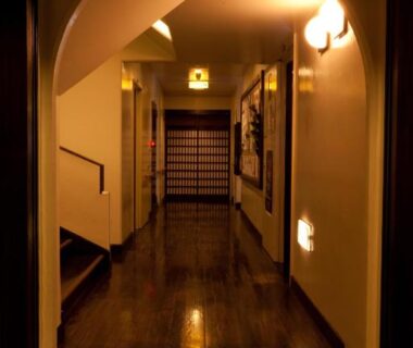 Polished wooden corridor with arched doorway, shoji screen and warm lighting at Kimi Ryokan in Tokyo