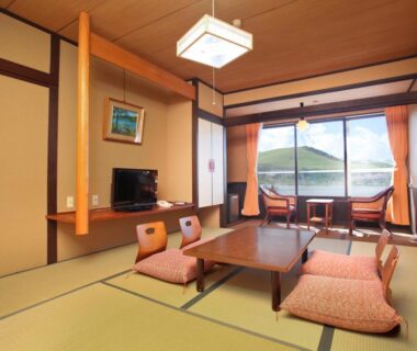 Tatami room with low table and zabuton cushions at Kimimachisou with hillside view in Nagano