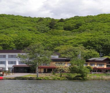 Waterfront ryokan buildings with dock and forested hillside in Nagano Chūbu region