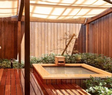 Square wooden onsen tub on sheltered deck with surrounding greenery at Kinnotake Saryo, Kanagawa