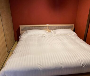 White striped duvet on double bed with red wall and bamboo screen at Kinnotake Saryo, Kanagawa