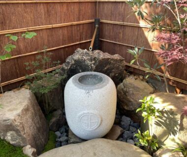 Stone garden basin with bamboo spout, rocks and maple near a bamboo fence at Kinnotake Saryo, Kanagawa