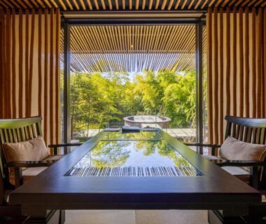 Traditional tatami room with low lacquer table, chairs and bamboo garden visible through sliding doors