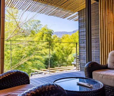 Wicker chairs and low table on glass balcony overlooking lush hillside at Kinnotake Sengokuhara, Kanagawa