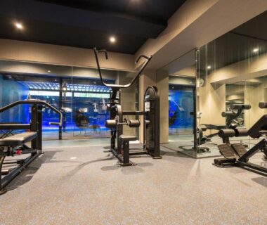 Modern fitness room with cardio and strength machines, mirrored wall and glass window at Kinnotake Tonosawa in Kanagawa