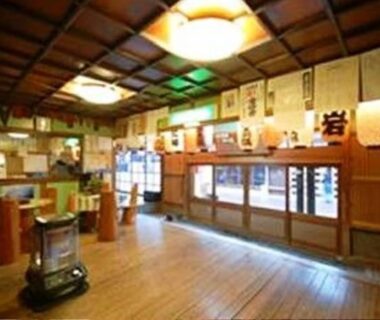 Wooden lobby with heater, low stools, shoji windows and hanging lanterns at Kinokuniya Jinpachi in Nara