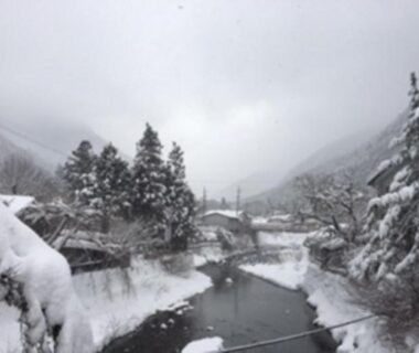 Snow-laden river and small bridge with traditional houses and pine trees near Kinokuniya Jinpachi, Nara, Kansai