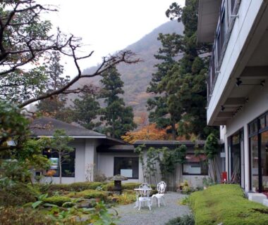 Courtyard garden with chairs at Kinokuniya Ryokan in Kanagawa with mountain backdrop