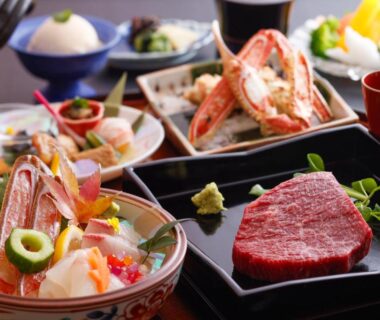 Japanese multi-course meal with sashimi bowl, crab, grilled steak, pickles and lacquerware table setting at a ryokan in Hyōgo