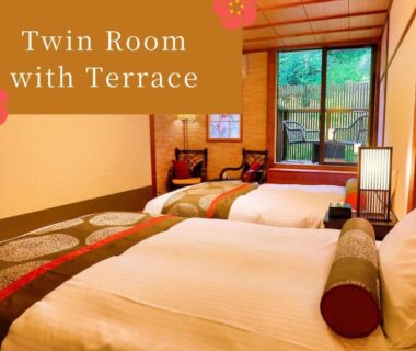 Tatami-style twin room with two beds and sliding door to wooden terrace at Kinosaki Tenboen, Hyōgo