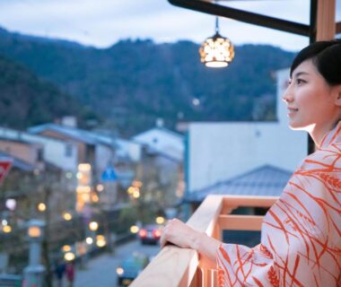 Woman in yukata on balcony overlooking Kinosaki town at dusk, Kinosaki onsen Tokitotoki, Hyōgo, Japan, Kansai