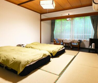 Tatami room with two futon beds, low seating by window, wooden ceiling at Kinosato Yamanoyu in Ōita