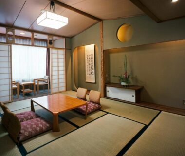 Tatami room with low table, zabuton cushions, shoji screens and tokonoma floral arrangement at Kinparo Kyoto