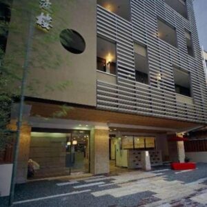 Exterior of Kinparo ryokan with slatted multi-story facade, kanji signage and ground-level entrance on Kyoto street