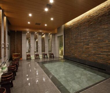 Communal indoor onsen pool with wooden stools and stone wall Kinparo Kyoto