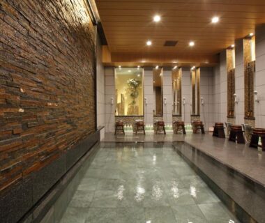 Indoor onsen bath with stone wall and wooden stools at Kinparo Kyoto