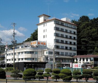Multi-story white ryokan building with landscaped shrubs and forested hillside in Mie, Kansai, Japan