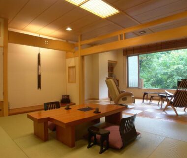 Sunlit tatami room with low table and lounge chairs by window at Kinseikan Seseragi, Gunma Kanto