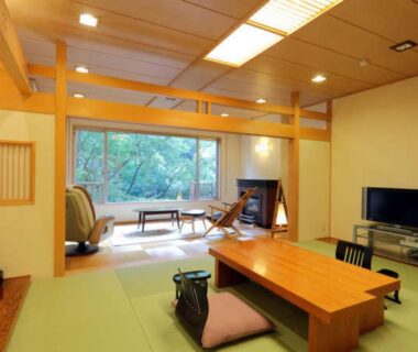 Tatami room with low wooden table, seating and garden view at Kinseikan Seseragi in Gunma