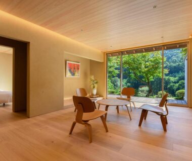 Spacious wooden floor sitting area with low table, chairs, shoji screen and garden view at Kinshuusanso in Gunma