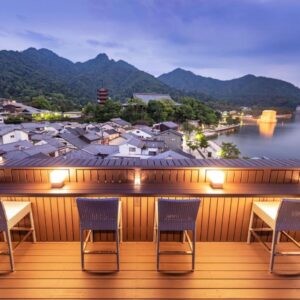 Wooden deck with chairs at Kinsuikan overlooking illuminated waterfront and mountains in Hiroshima, Chūgoku